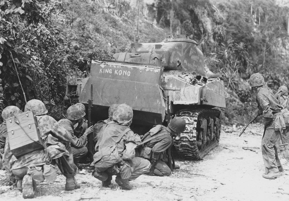 Marines take cover behind an M4 medium tank, Saipan 1944