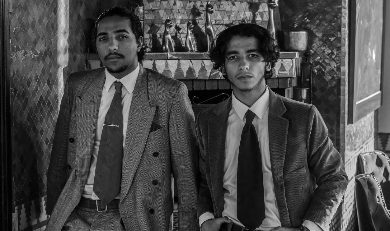 Two men wearing suits and looking at the camera