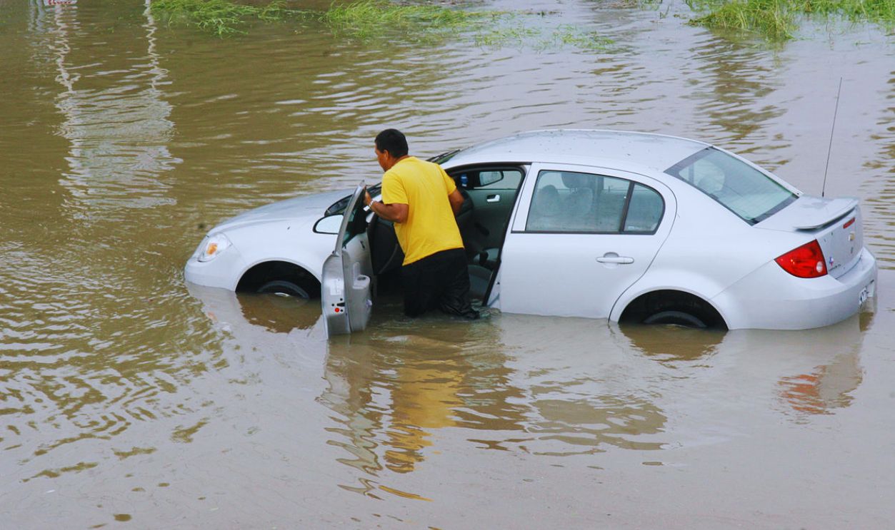 Resident pushing a car through flood waters in Texas