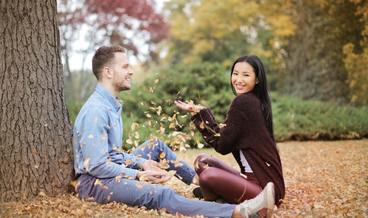 Happy couple scattering leaves in park