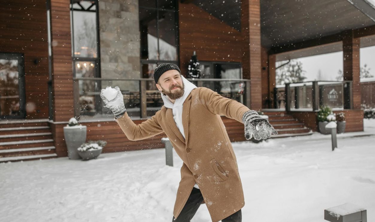 A Man in Brown Coat Playing Snow