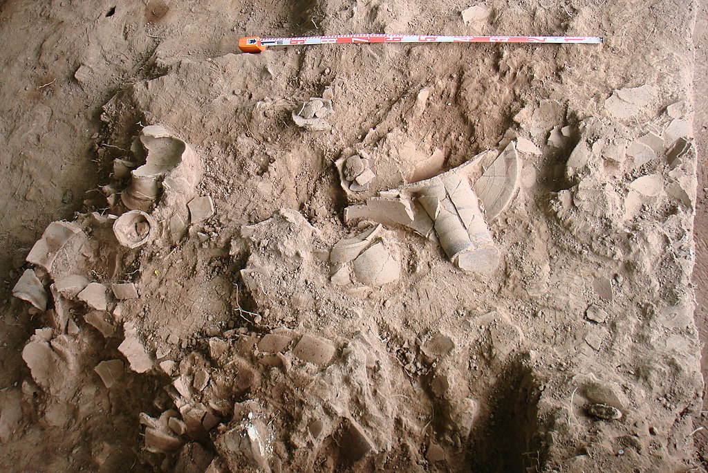 Photograph of broken ceramics in an excavation unit from An Son, Vietnam. A meter stick is along the top of the photograph for scale.