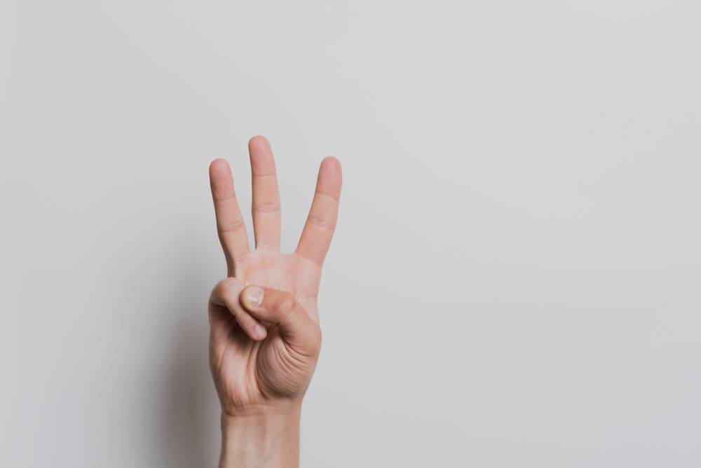 Caucasian male hand shows gesture number three