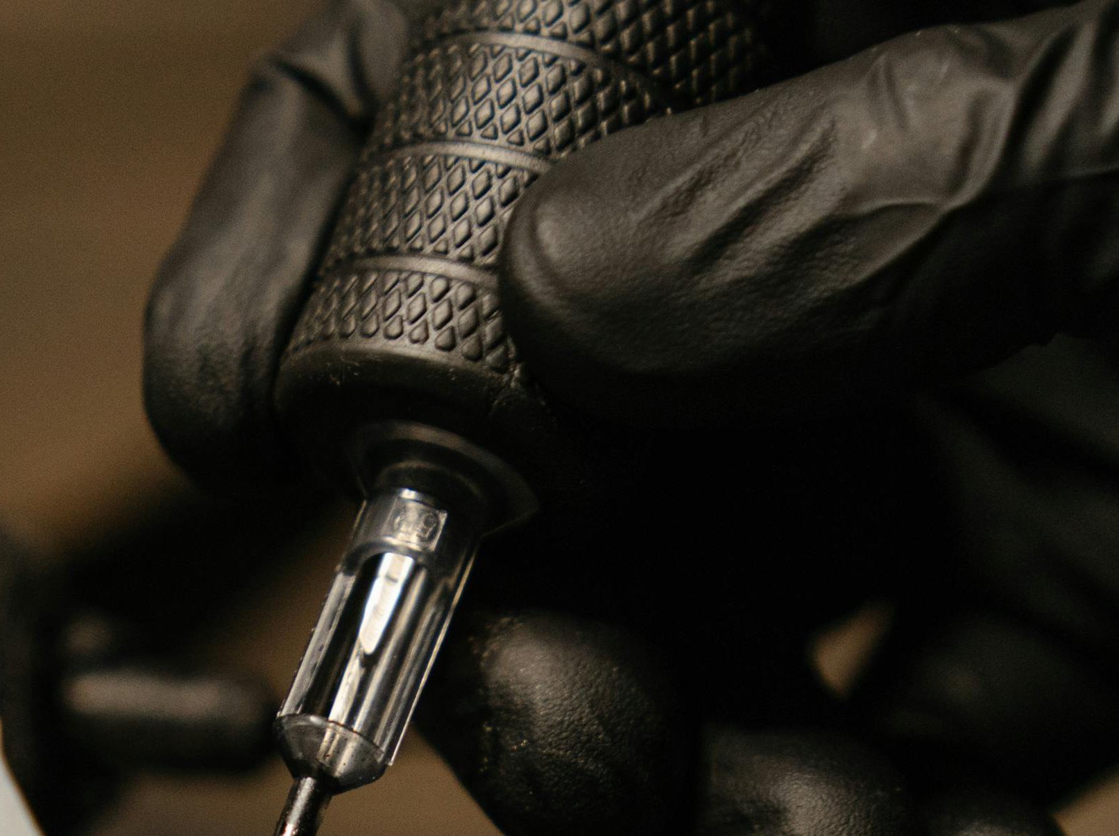 Tattoo machine being held by a hand wearing a black nitrile glove