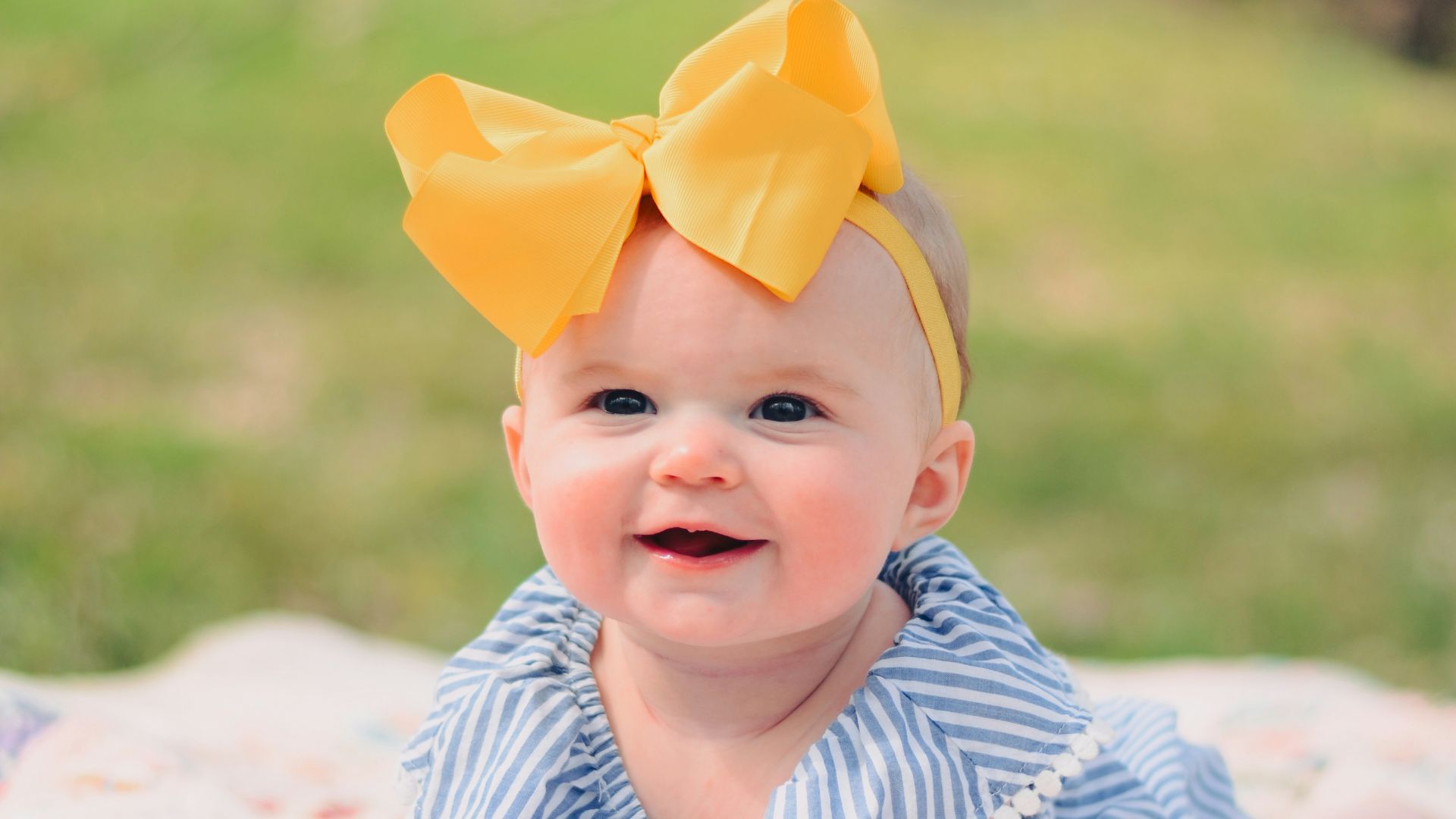 smiling baby lying forward on pink textile