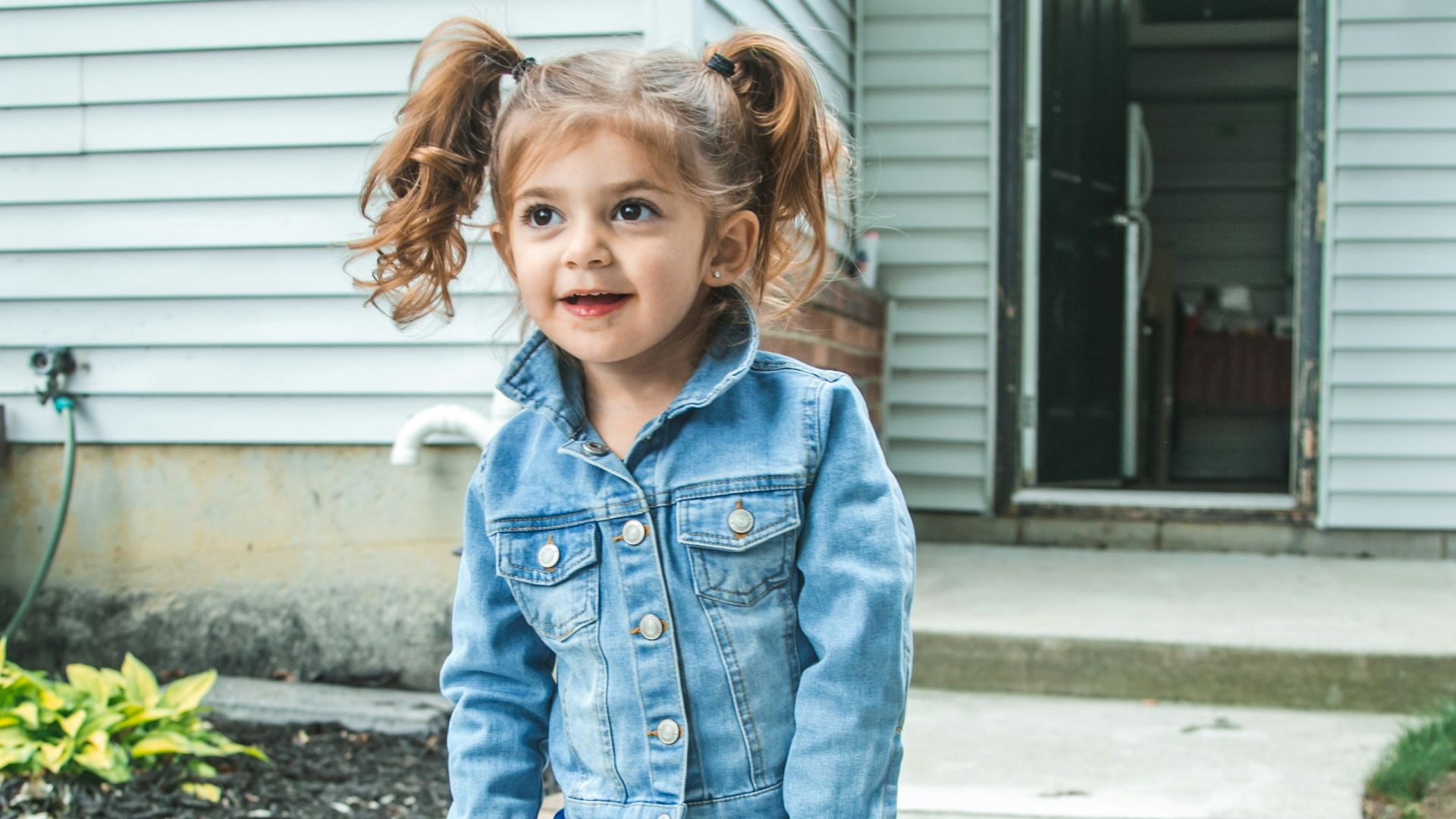girl in blue denim jacket and blue denim jeans standing on gray concrete floor during daytime
