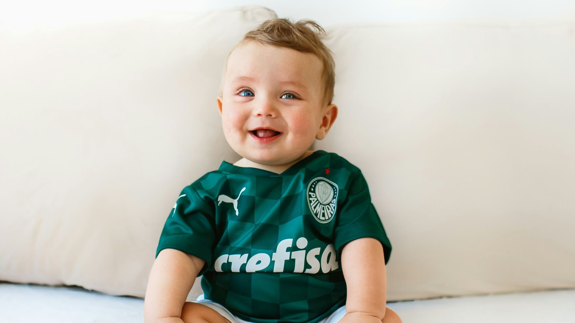 boy in green and white crew neck t-shirt sitting on white bed