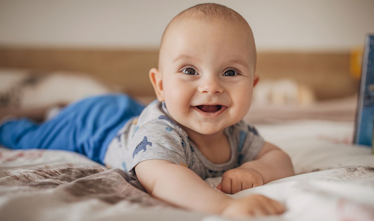 One boy, beautiful baby boy lying on bed and smiling.
