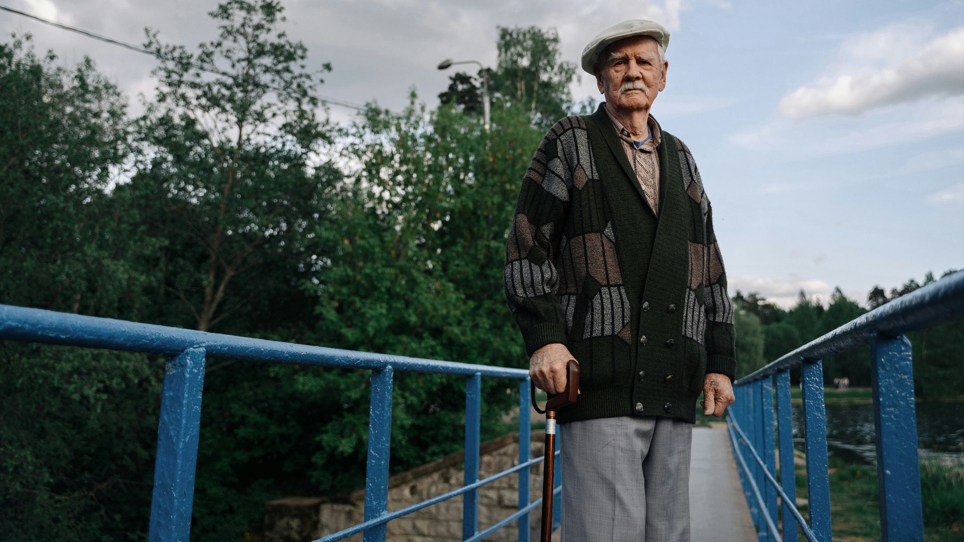 man in black and brown plaid dress shirt standing beside blue railings