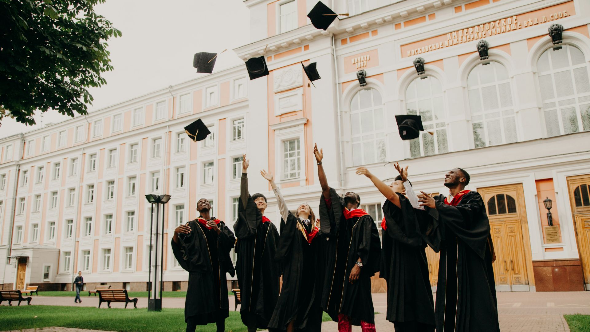 people in black academic dress standing on green grass field during daytime