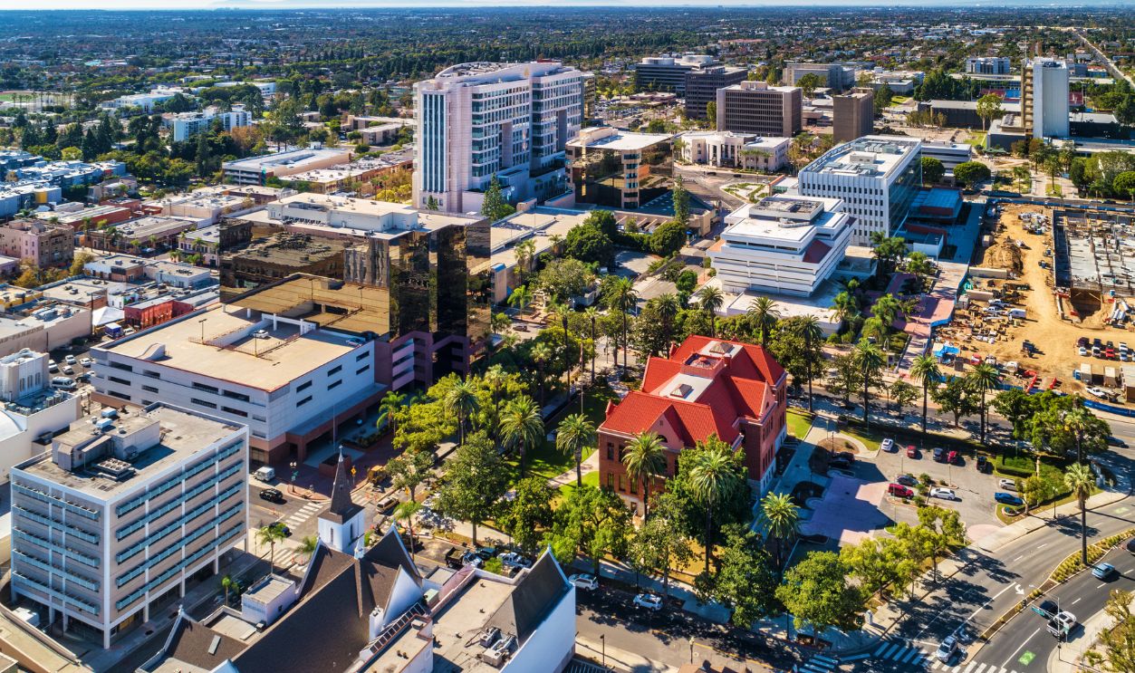 Aerial view of Downtown Santa Ana, with various highrise buildings, and the Old Orange County Courthouse with trees in the foreground.