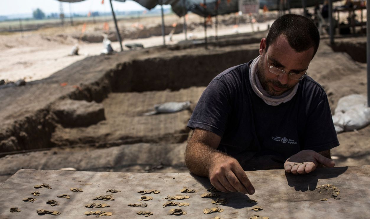 Israeli archaeologist Shahar Krispin ,35, counts gold coins dating to the Abbasid Caliphate during a press presentation of the discovery at an archeological site near Tel Aviv in central Israel, on August 18, 2020. Israel's Antiquities Authority unveiled a trove of 425 gold coins said to be some 1200 years old, discovered in what was an industrial area during the Byzantine Period.