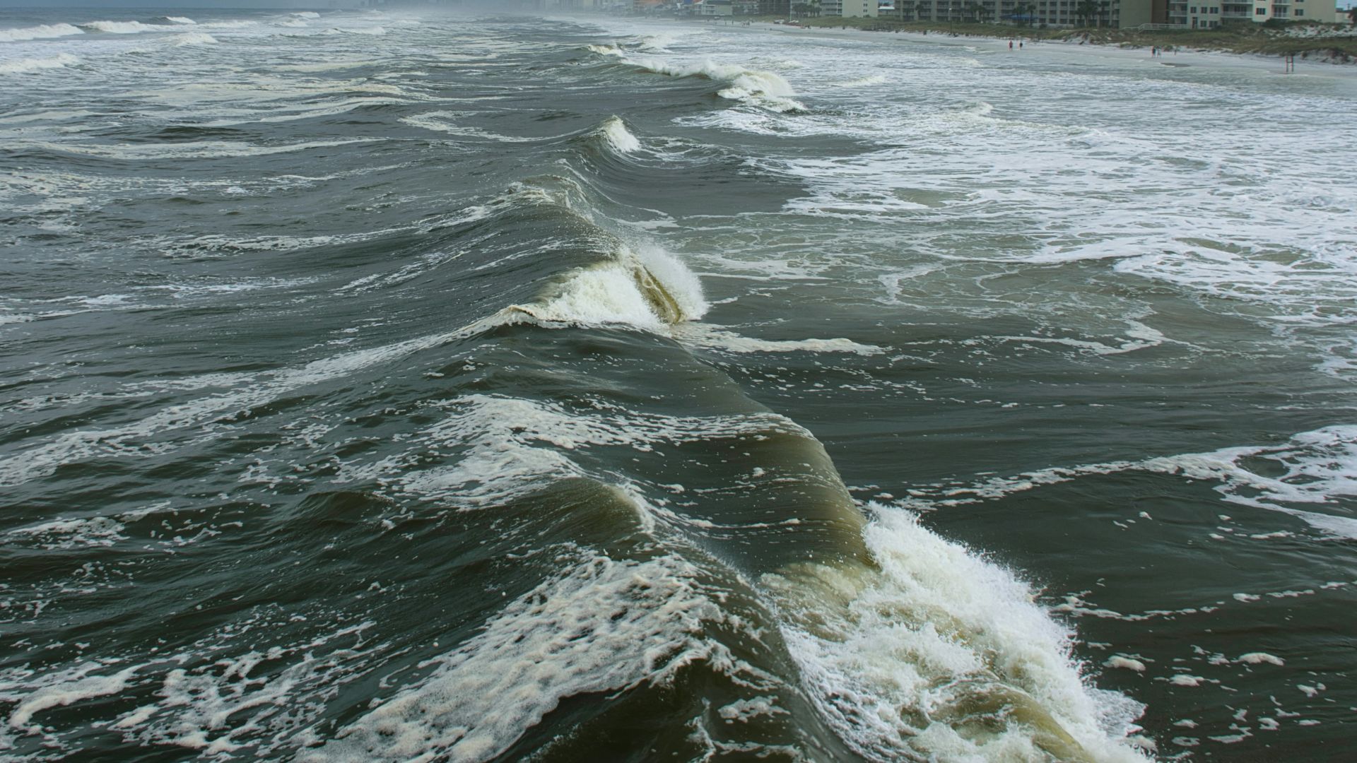 ocean waves near city buildings during daytime