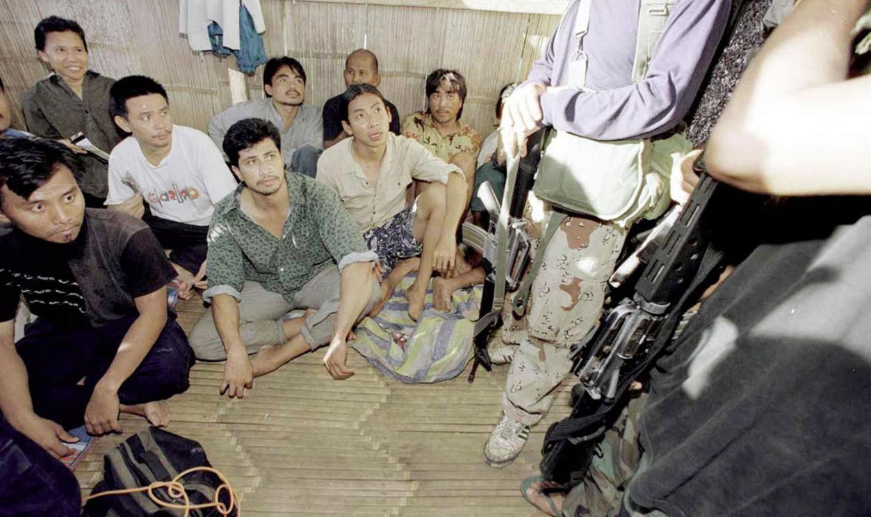 Malaysian Hostages Are Guarded By Two Muslim Rebels Armed With Assault Rifles While Being...