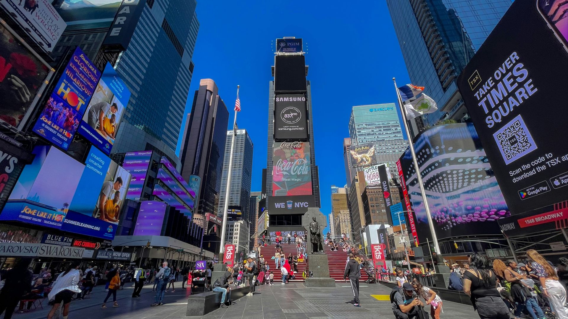 a crowd of people walking around a city with tall buildings