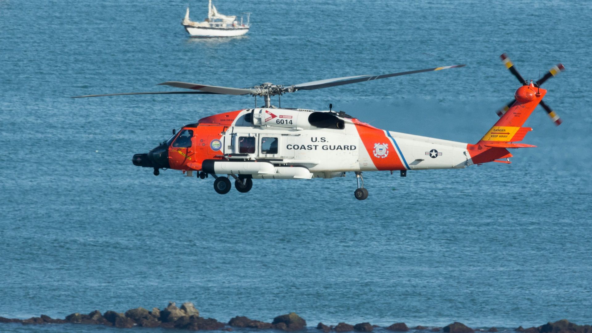 white and orange helicopter on body of water during daytime