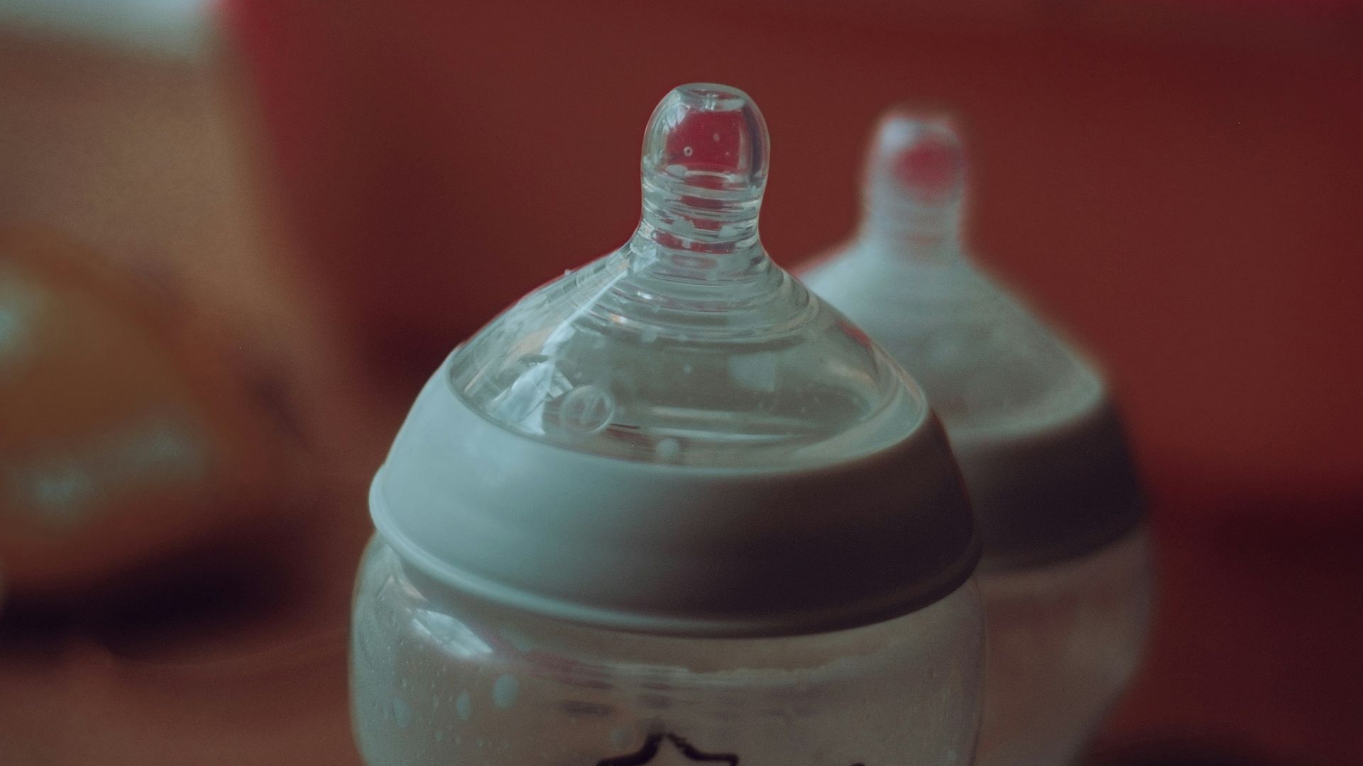 clear plastic feeding bottle on red table