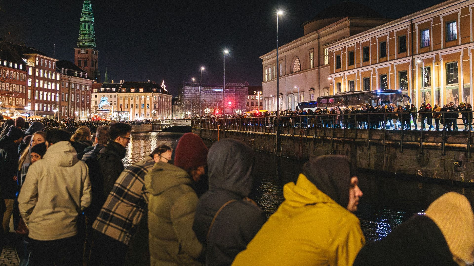 Crowd gathered by canal at night in city