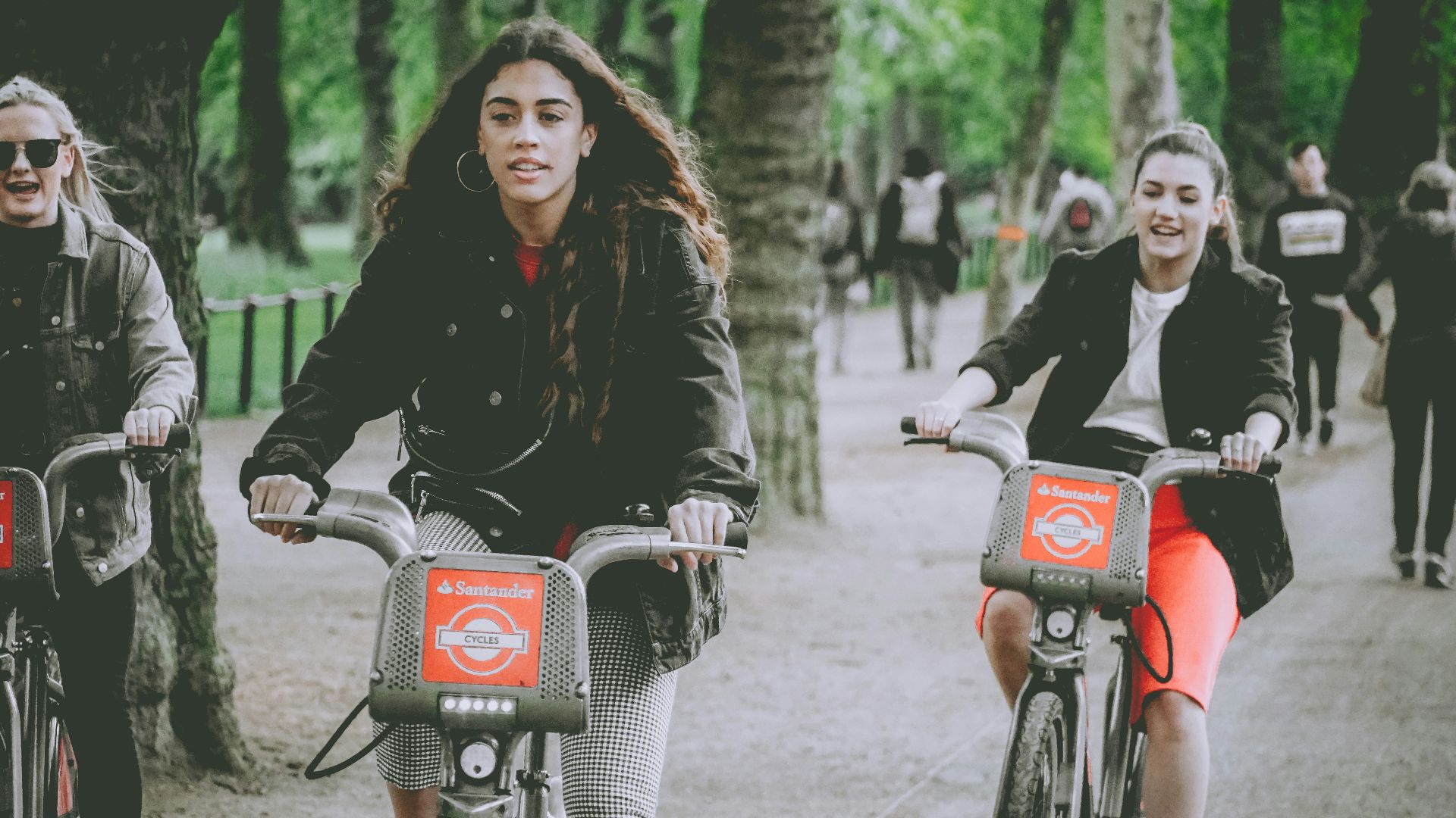 three women riding bicycles on parked