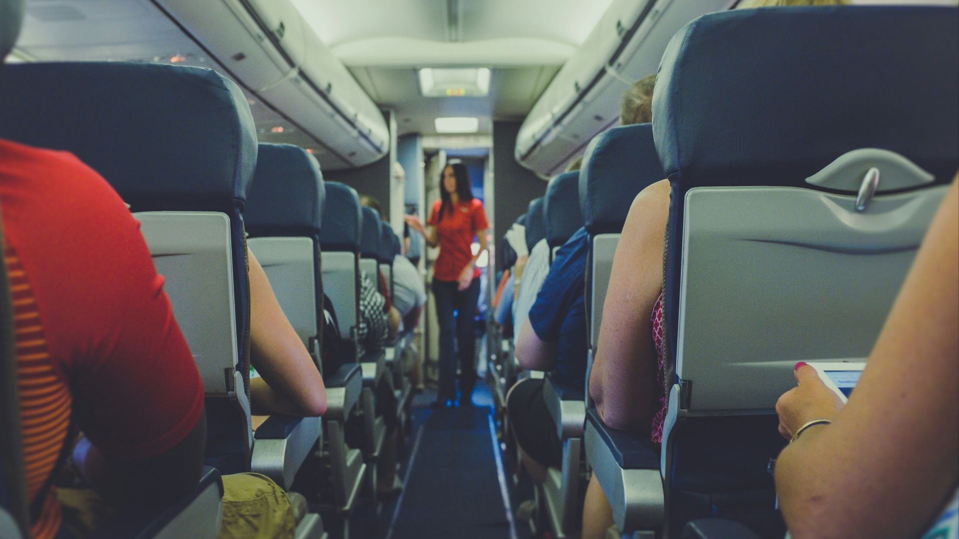 flight attendant standing between passenger seat