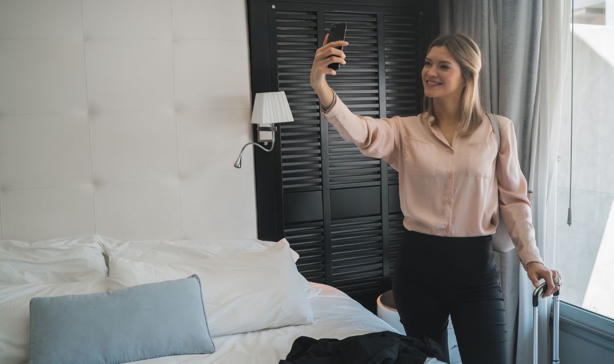 Portrait of young businesswoman taking a selfie with phone at the hotel room. Business travel concept.