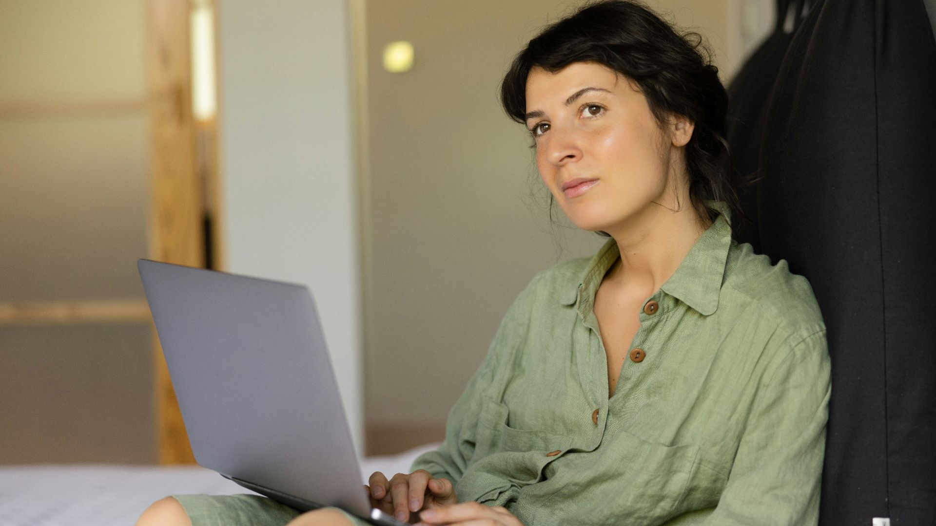 a woman sitting on a bed using a laptop computer