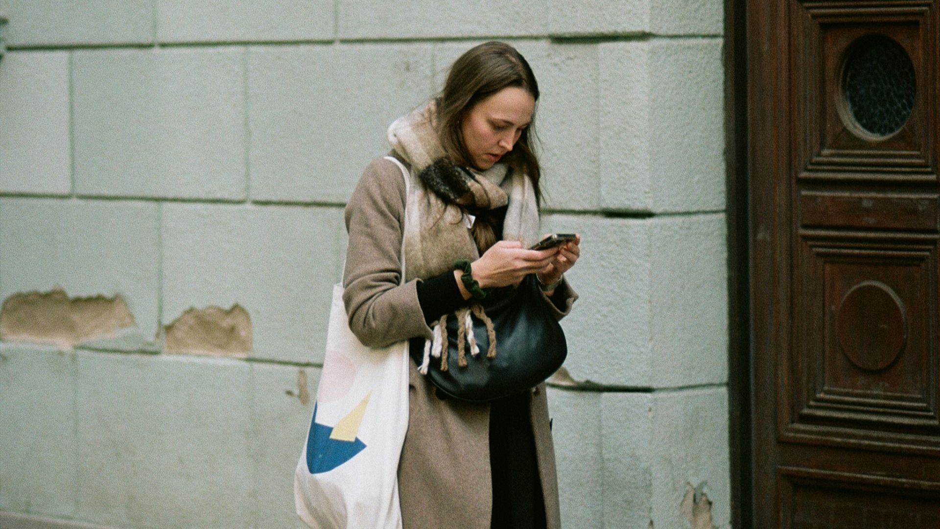 A woman standing on a sidewalk looking at her cell phone