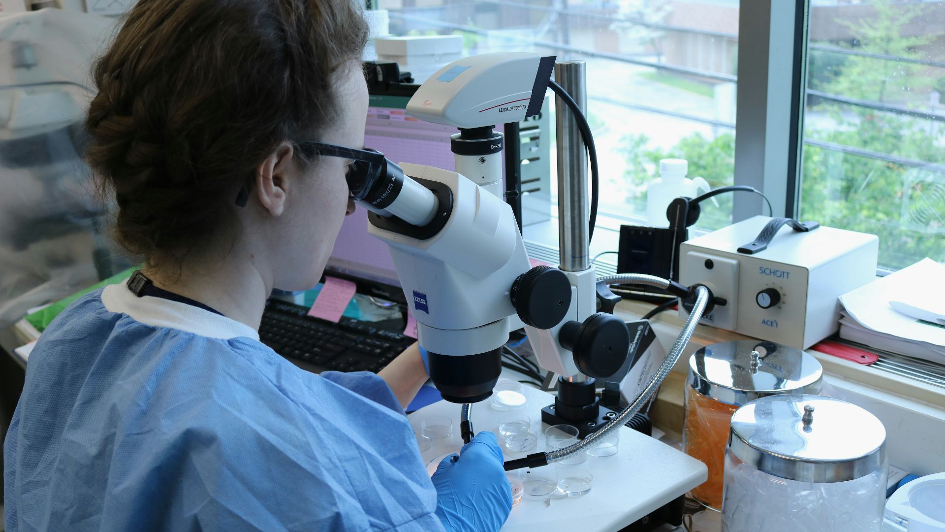a woman in a lab coat looking through a microscope
