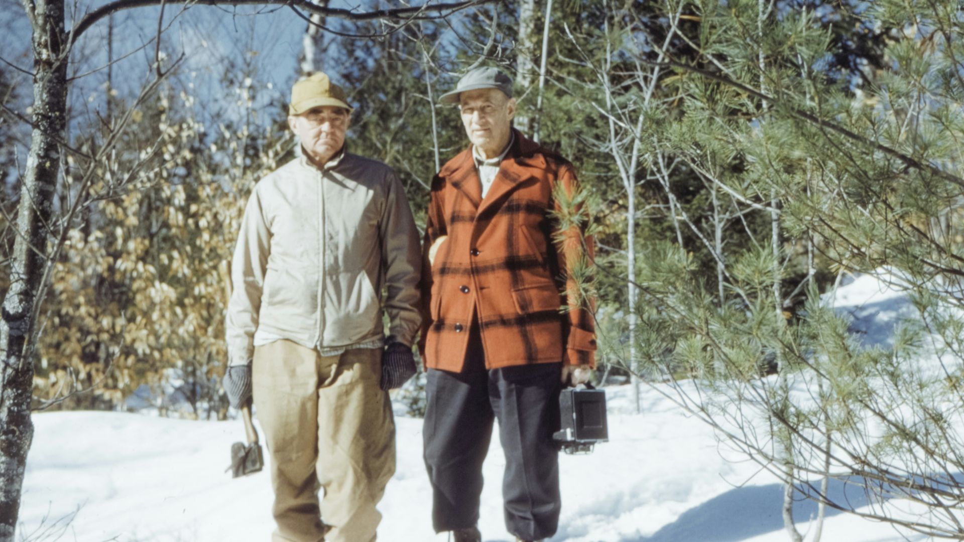 man in brown jacket standing on snow covered ground during daytime