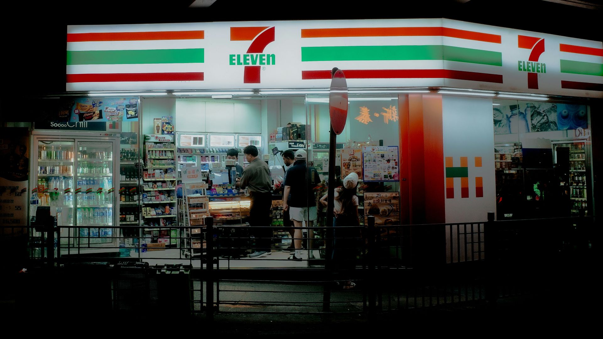 A convenience store at night with people standing outside