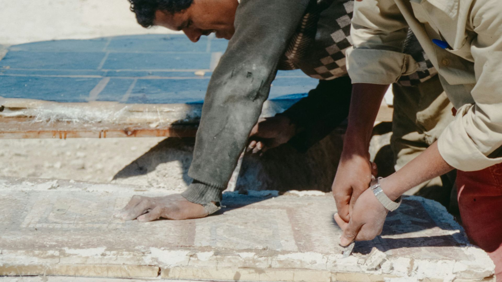 Two young men working on stone blocks outdoors.