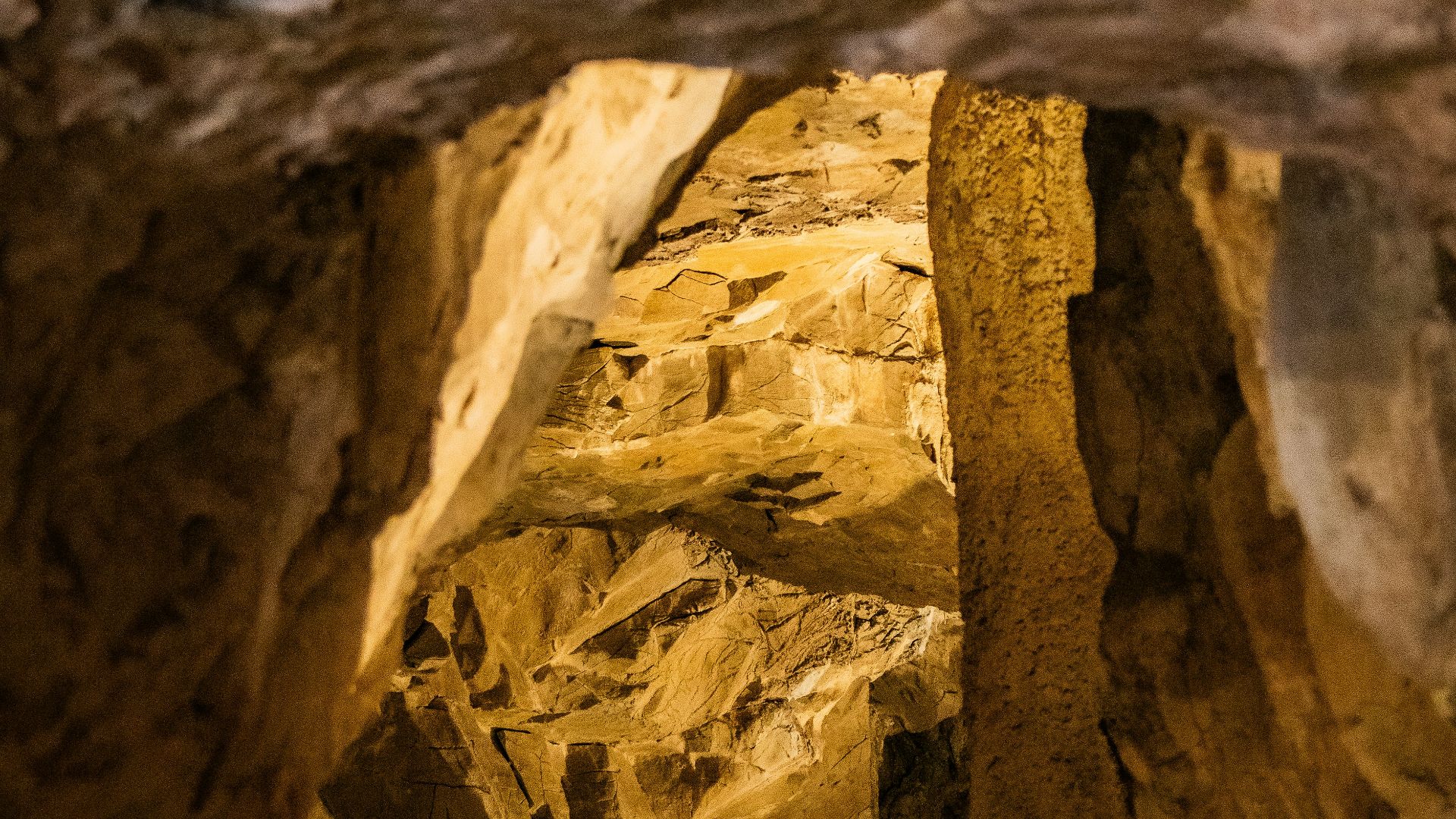 Illuminated cave interior with rough rock formations.