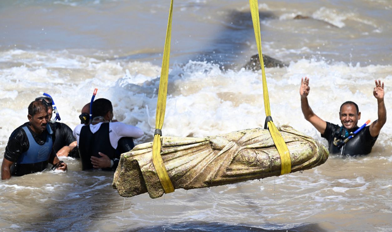 Gettyimages - 2230470527, EGYPT-ARCHAEOLOGY Divers celebrate as a crane pulls an artifact from the waters at Abu Qir bay in Alexandria on August 21, 2025, as part of an event organized by the Ministry of Tourism and Antiquities to recover sunken antiquities.