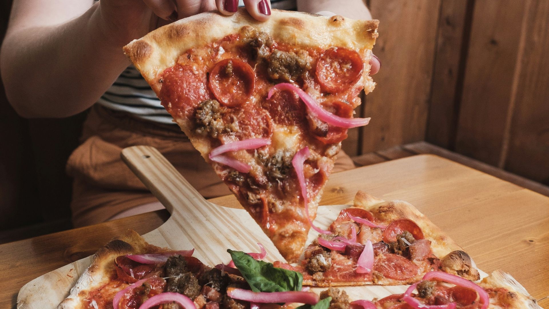 a woman is taking a slice of pizza