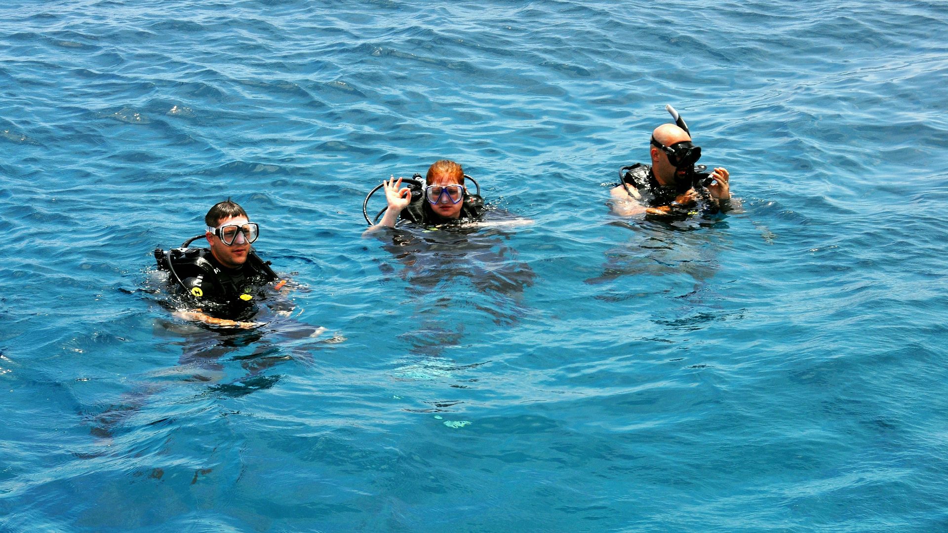three people in the water wearing scuba gear