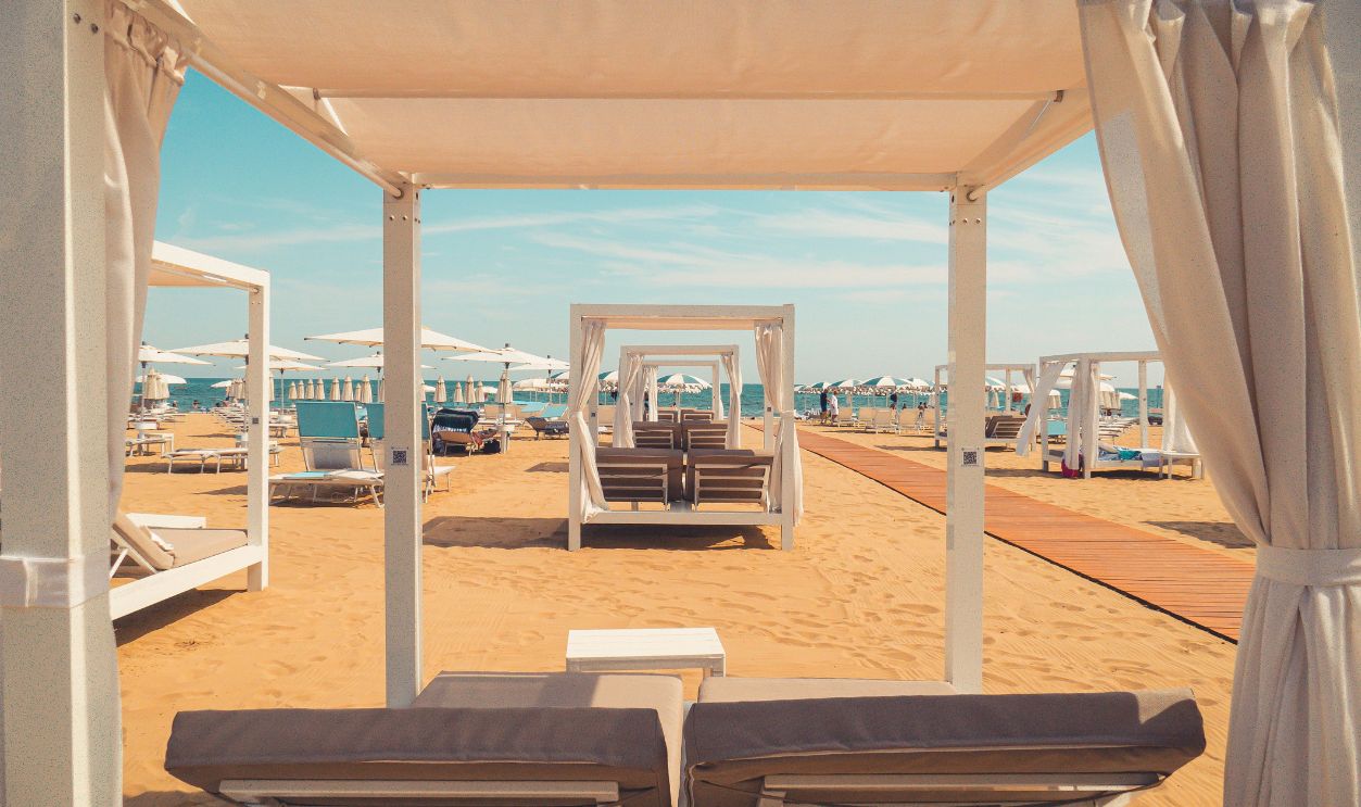 Elegant cabanas set up on a sandy beach, perfect for a relaxing summer day by the sea.