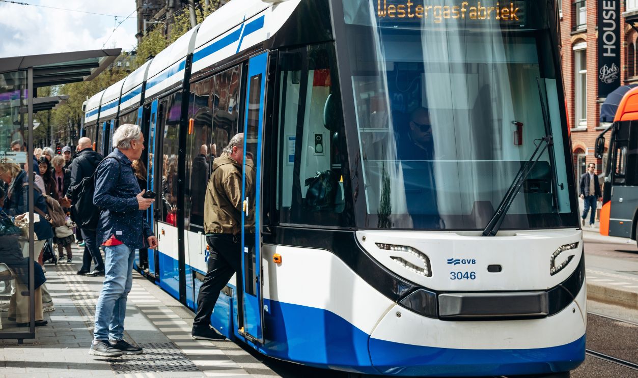 Amsterdam, Netherlands - April 19, 2026: Modern blue and white GVB tram at a busy city stop in Amsterdam, with passengers boarding public transport in the Dutch capital