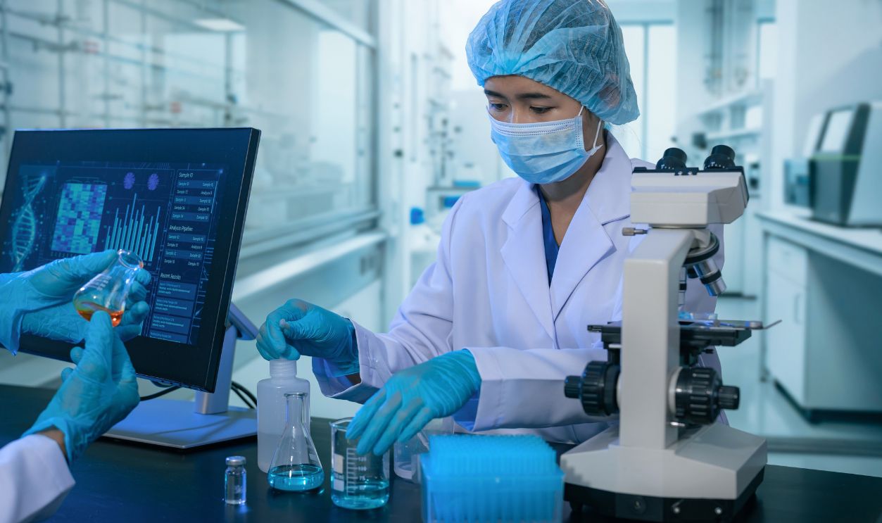 Biomedical researchers working with microscope and chemical samples for vaccine development and disease research.