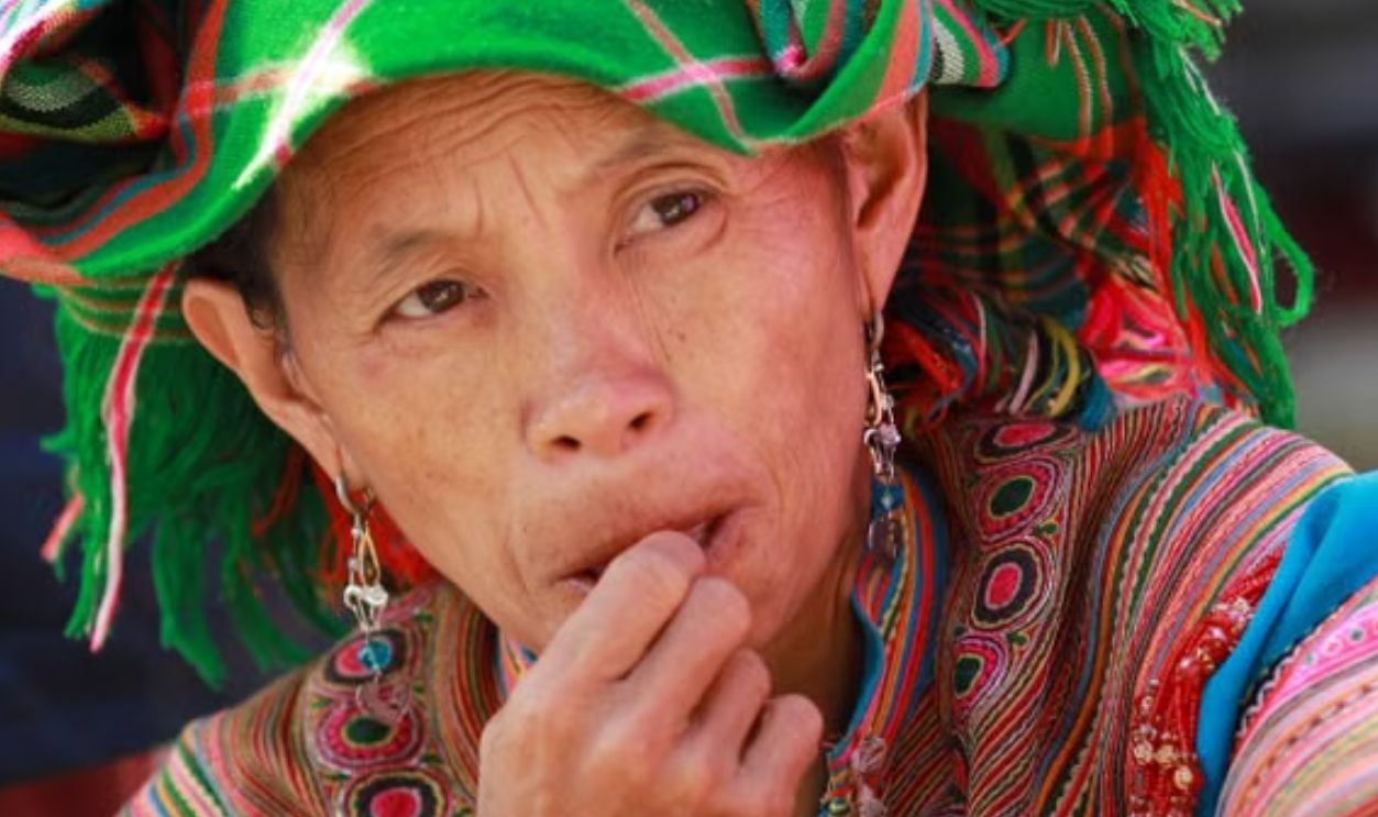 Hmong woman in colorful traditional attire at Lao Cai market, showcasing cultural heritage