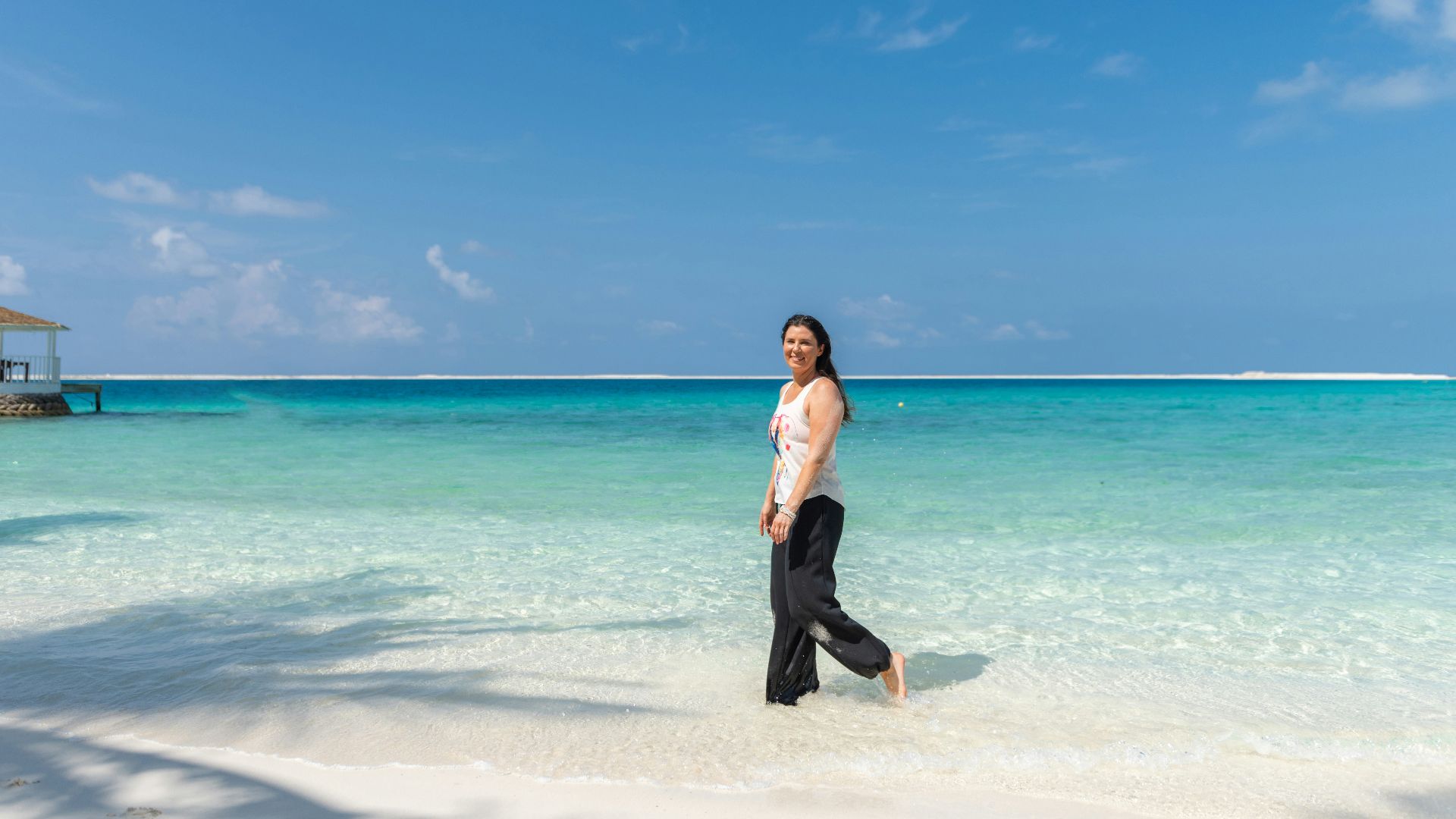 Woman walking on a tropical beach with clear blue water
