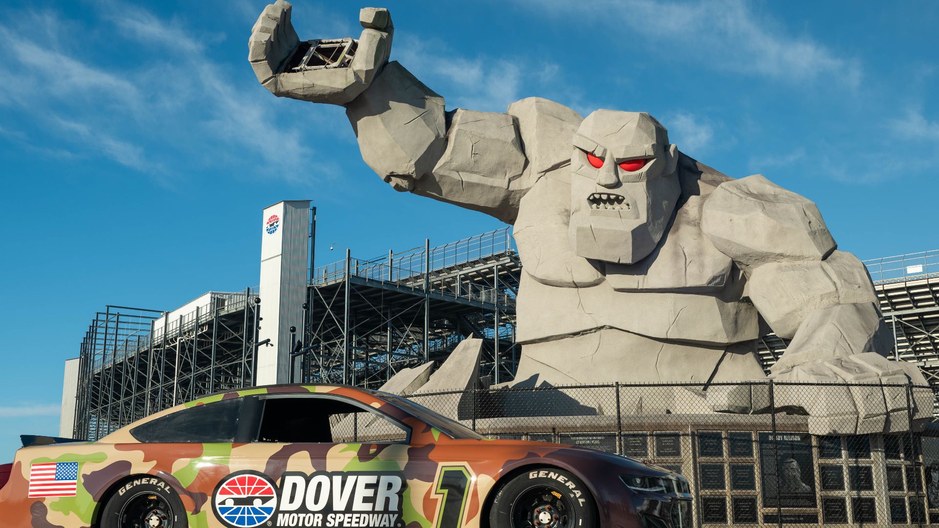 “Miles the Monster” and the Dover Motor Speedway model car are displayed at Dover Motor Speedway, Dover, Delaware, April 8, 2024. The model car, painted with a camouflage pattern, celebrates the relationship between the speedway and Dover Air Force Base. 