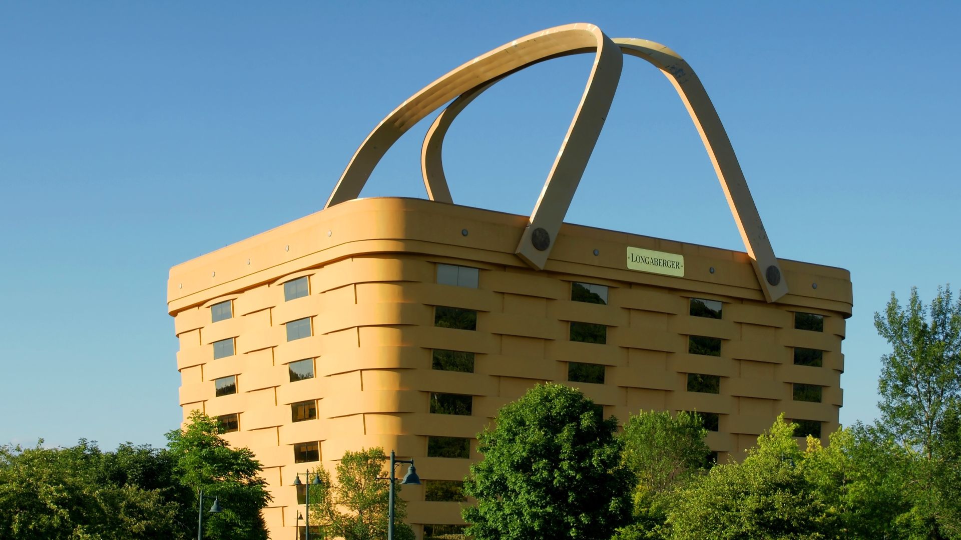 Image of Longaberger building in Newark Ohio on a clear cloudless day just before sunset with trees and the driveway in the foreground and the building in the background