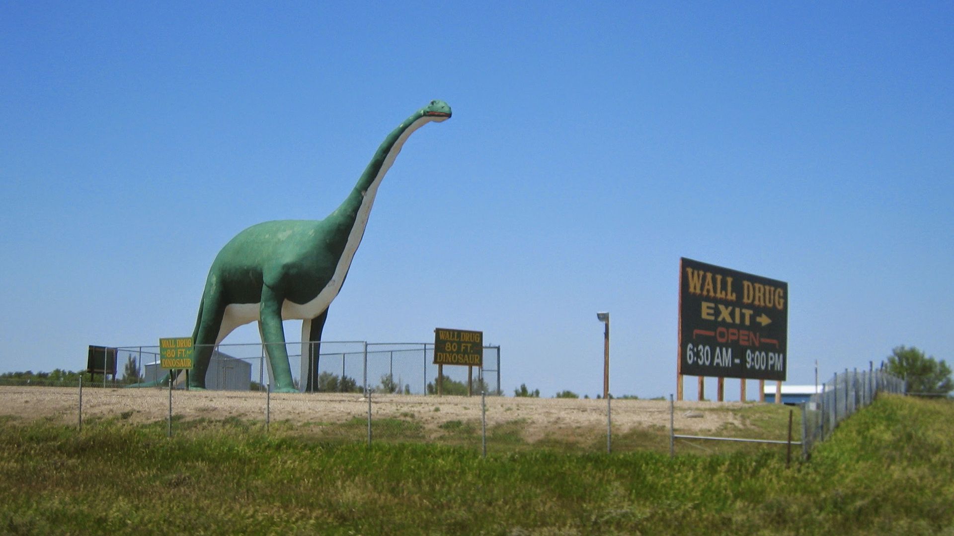 advertisement for Wall Drug Store in western South Dakota, including a large sculpture of a Brontosaurus