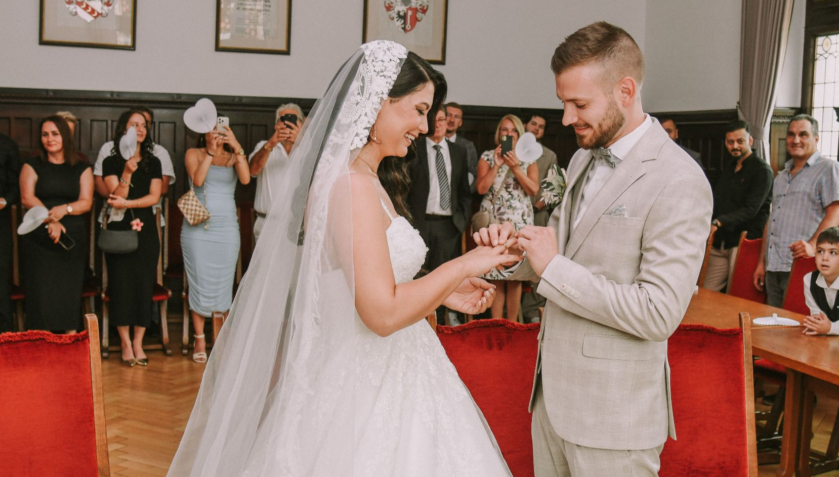 Bride and groom exchanging rings in a beautiful wedding ceremony indoors with guests.