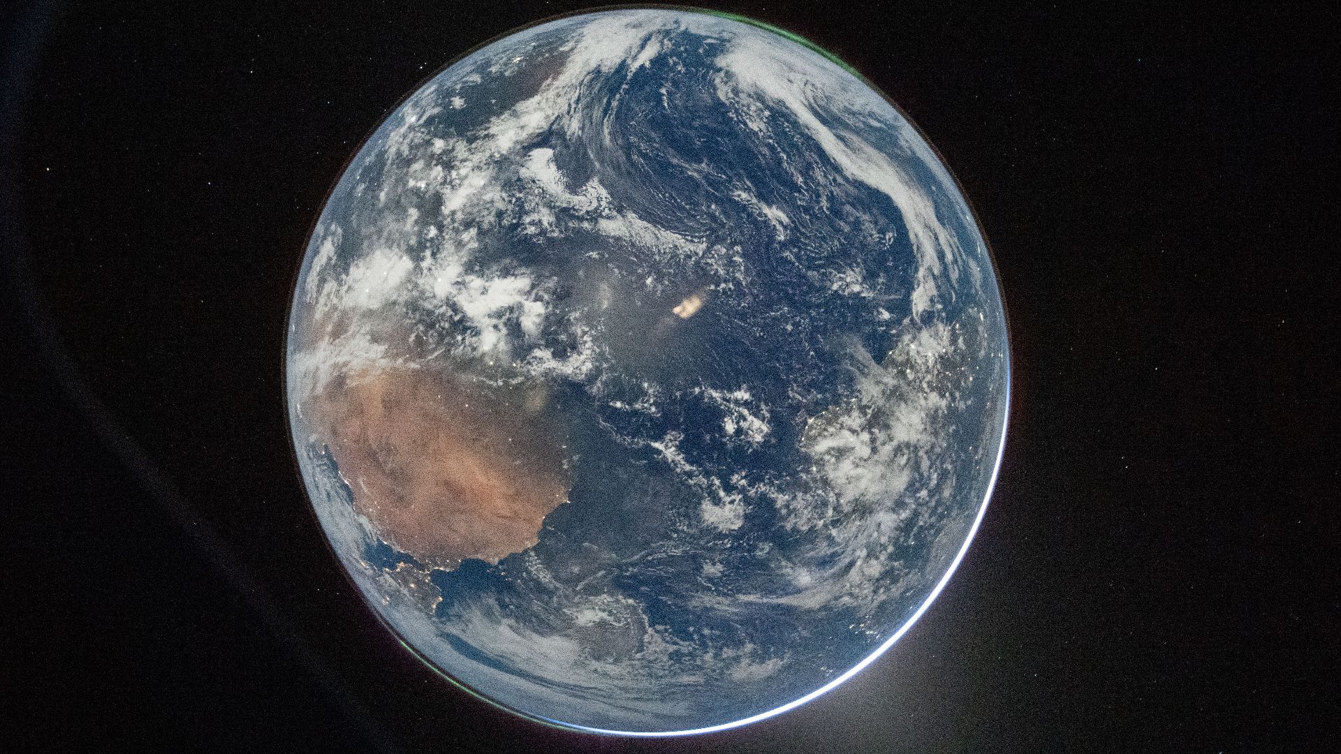 A view of Earth taken by NASA astronaut and Artemis II Commander Reid Wiseman from of the Orion spacecraft's window after completing the translunar injection burn on April 2, 2026. The image features two auroras (top right and bottom left) and zodiacal li