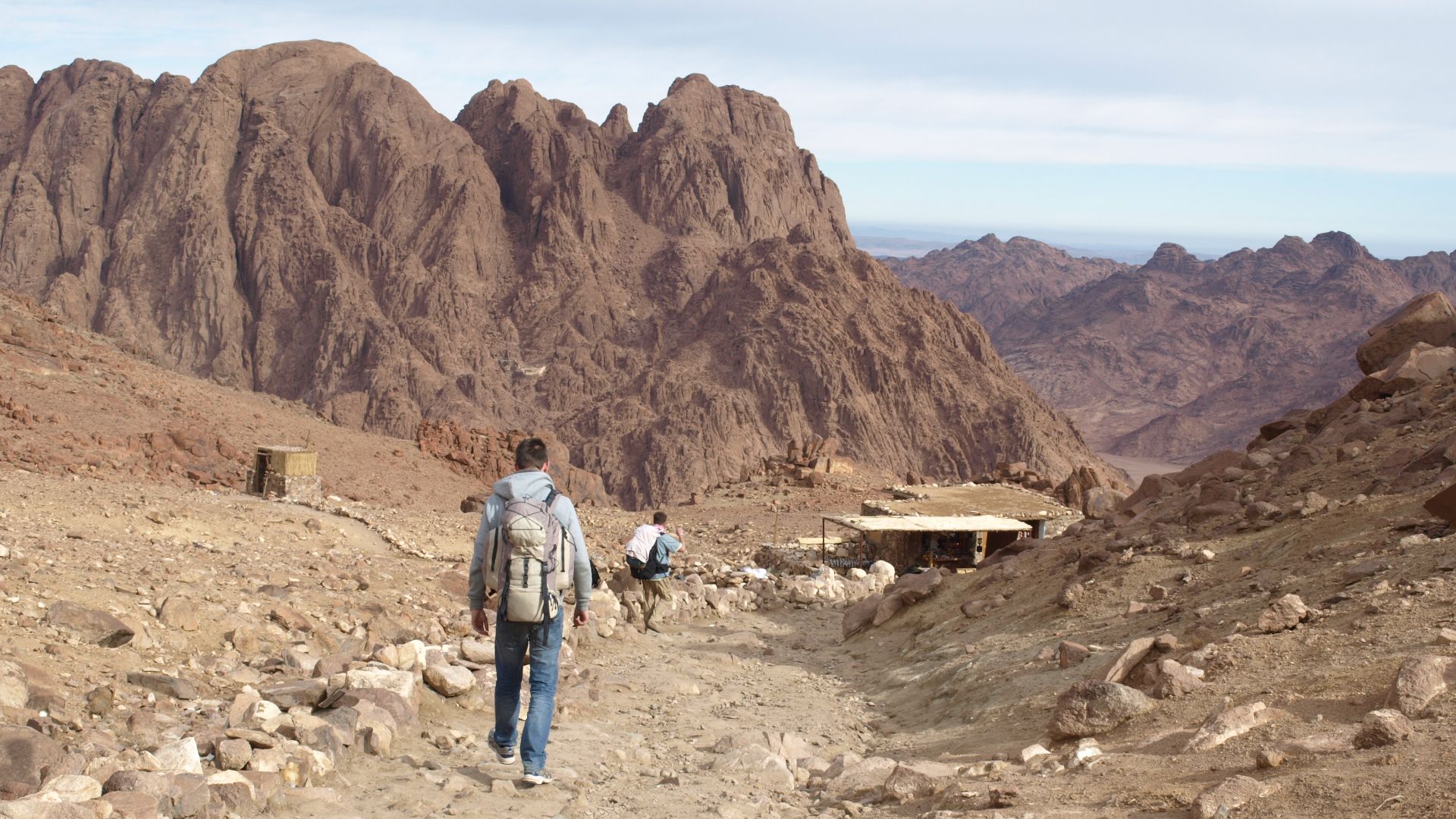 Pilger beim mittaglichen Abstieg vom Berg Sinai. Unmittelbar um Sonnenauf- und -untergang drängen sich hier hunderte Pilger auf dem teilweise steilen Stücken. Im Hintergrund sieht man eines der vielen Teehäuser, welche für die Verpflegung der Pilger sorge