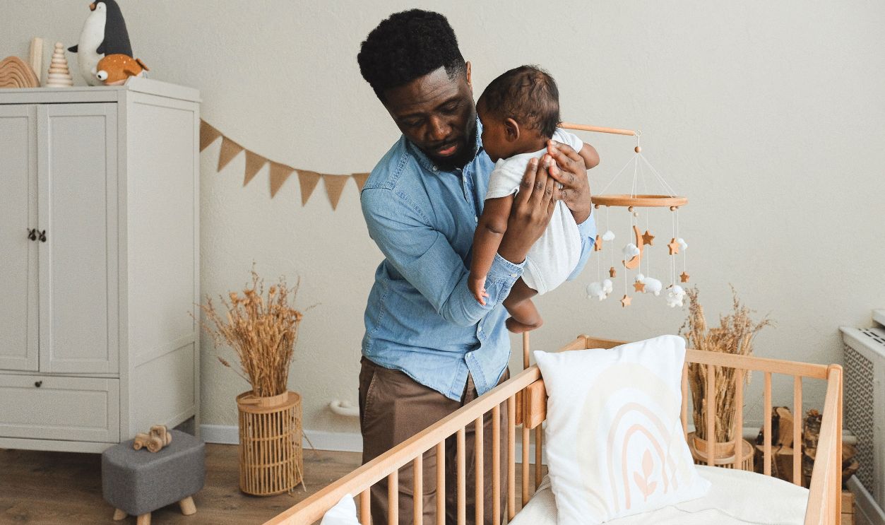 A loving father gently placing his baby in a cozy crib