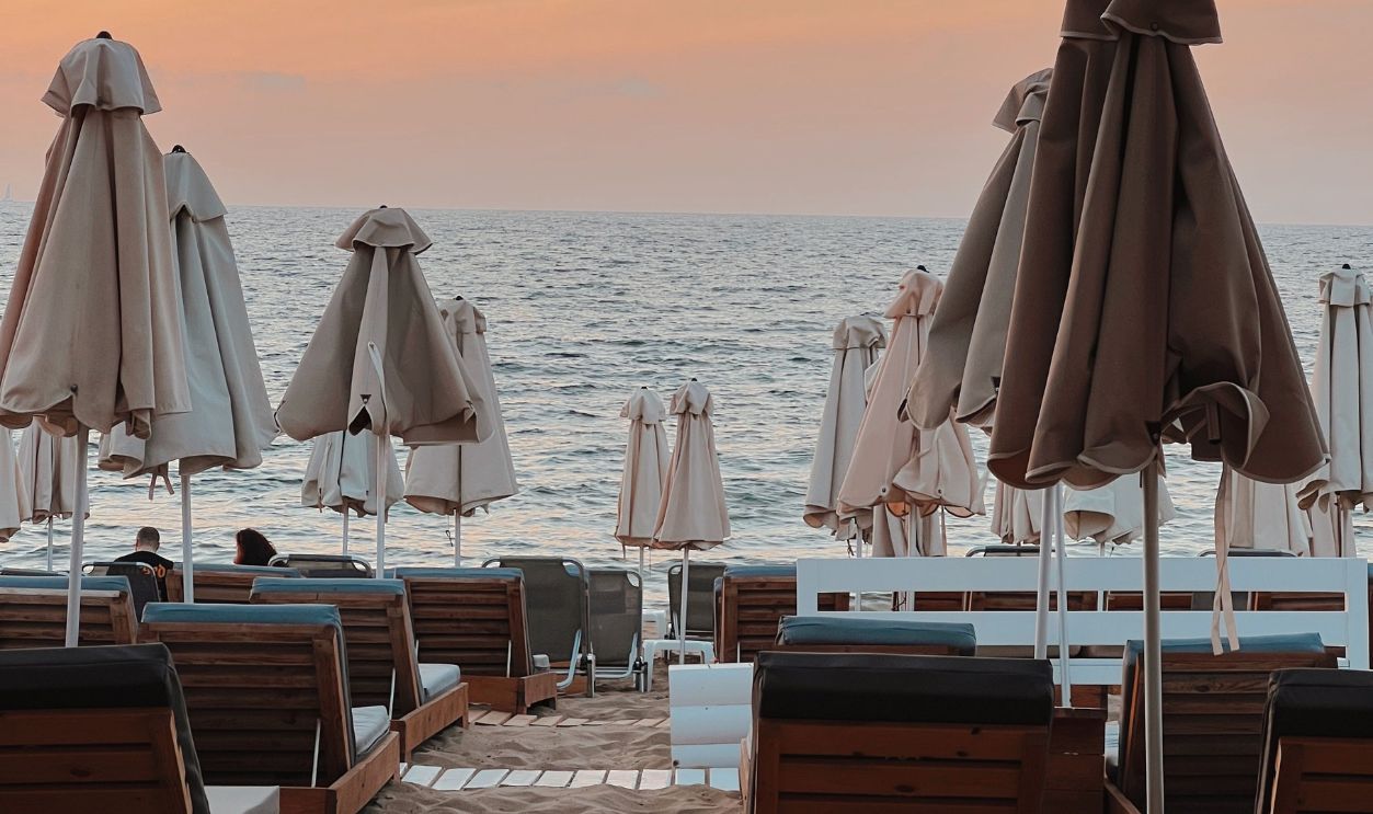 A tranquil beach scene at sunset with lounge chairs and umbrellas overlooking the sea