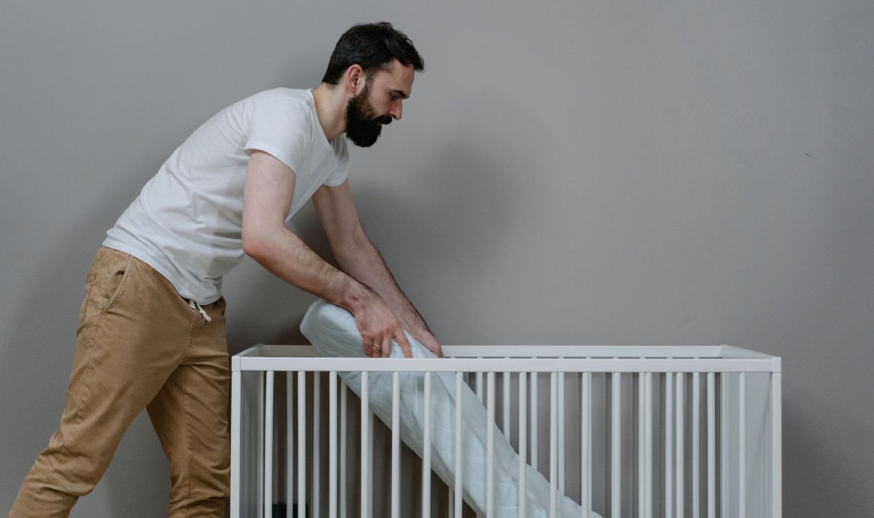 A bearded man setting up a crib