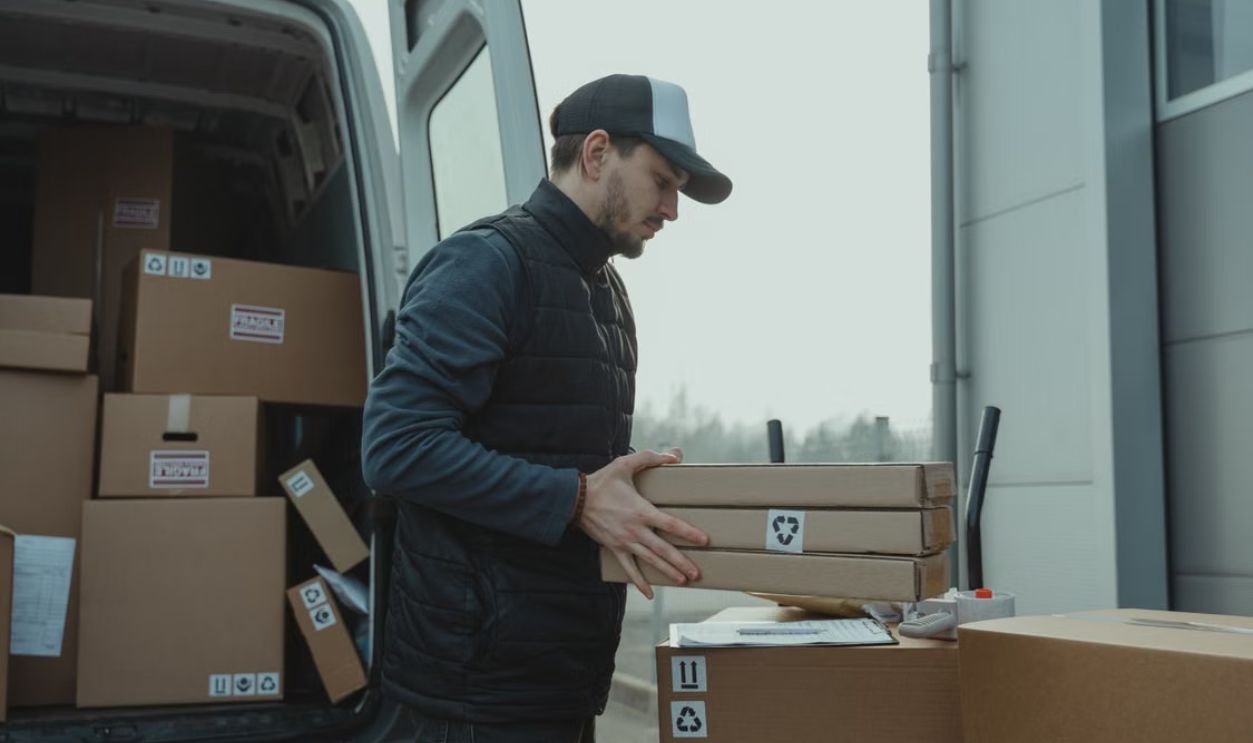 Delivery driver handling cardboard boxes during shipping at a commercial building.